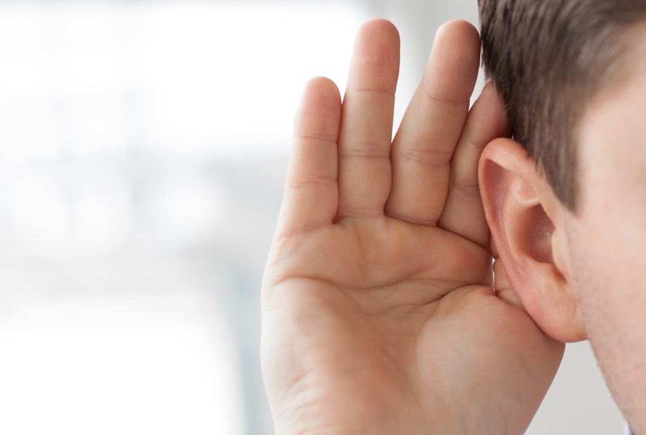 Nærbillede af øre. Personen holder sin hånd bag øret for at lytte bedre.
